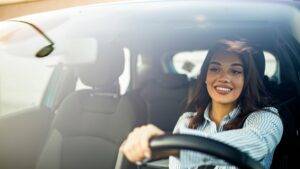 Smiling woman driving a car, highlighting the benefits of business car leasing.