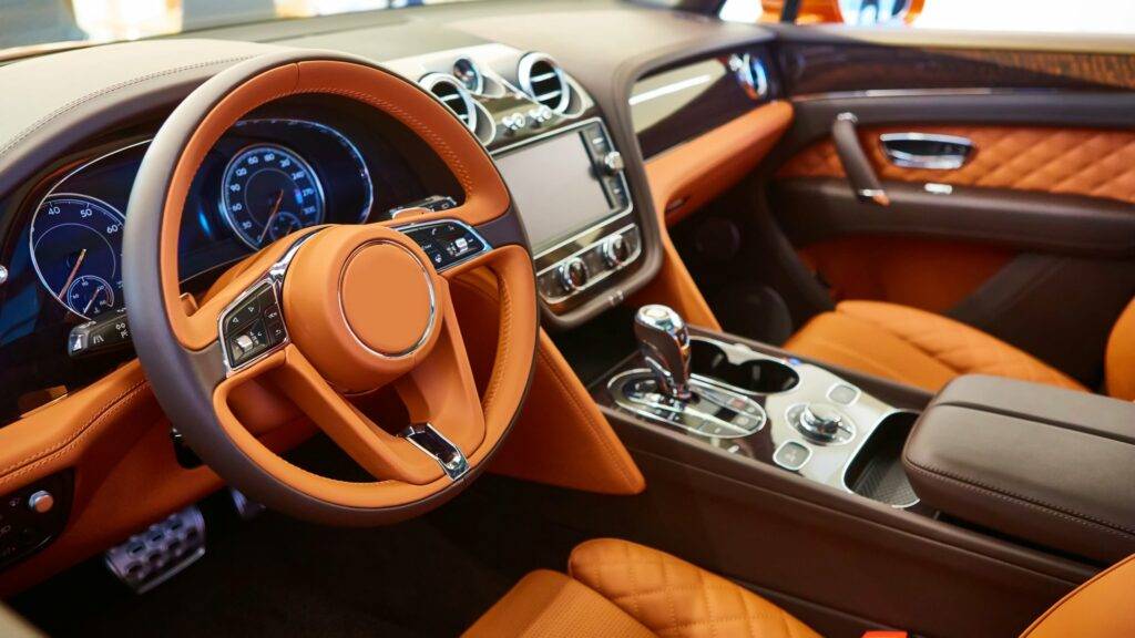 Luxurious car interior with leather seats, modern dashboard, and elegant steering wheel.

