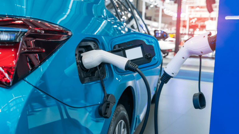 Close-up of a blue electric vehicle with charging connectors plugged in at a showroom.