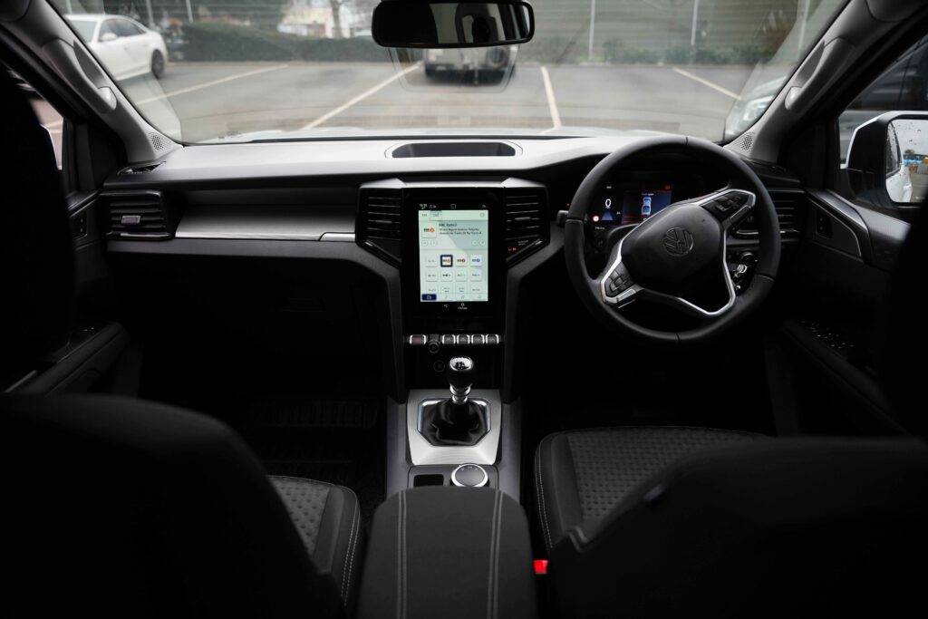 Interior view of a Volkswagen car showing steering wheel and central console in an empty parking lot